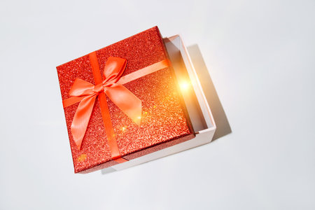 Shiny holiday red gift on a white background with a spark that is visible from the open package. Flat layの写真素材