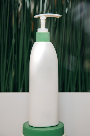White cosmetic packaging, a jar with a dispenser on a green background. Front viewの写真素材