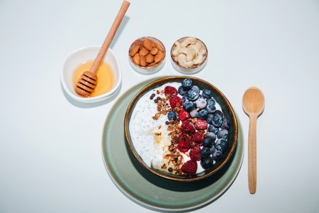 Yoghurts in green plate with blueberries, raspberries, chia seeds and granola on a white background. The concept of healthy eating. Top viewの写真素材