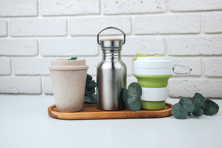 Set of devices for cold and hot drinks. Zero waste concept. A tin bottle for water and a mugs for coffee, tea on a wooden handle. Front viewの写真素材