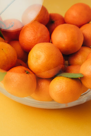 Orange mandarins clementine with green leaves in round clear vase close up. Front viewの写真素材
