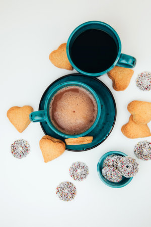 Two mugs of coffee with foam and a plate with heart-shaped shortbread cookies on a white background. Tpo viewの写真素材