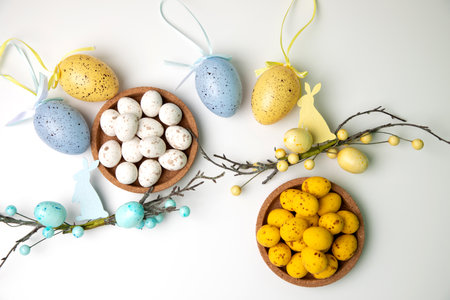 Multi-colored chocolate decorative eggs in wooden plates on a white background with decorative...