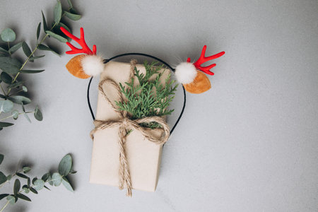 A gift wrapped in brown paper and decorated with a thuya branch and deer antler on a gray concrete background with a eucalyptus branch. Flat layの写真素材