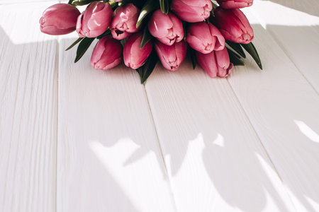 Pale pink delicate tulips on a white wooden background. Spring background with a bouquet of flowers. Top viewの写真素材