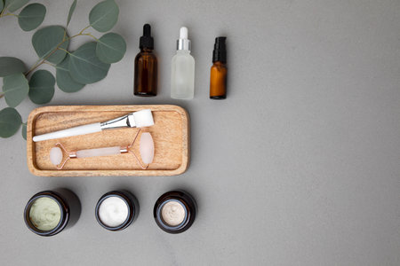 Amber bottles with facial cosmetics on a tray with a branch of eucalyptus on the gray concrete background. Top viewの写真素材