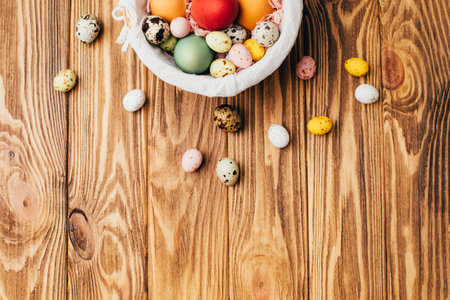 Colored eggs of different sizes in a straw basket on a wooden background. Symbol of the Easter holiday. Easter background. Top viewの写真素材