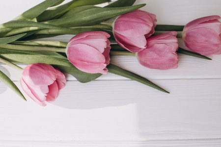 Pale pink delicate tulips on a white wooden background. Spring background with a bouquet of flowers. Top viewの写真素材