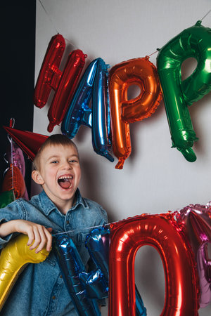 Childrens birthday celebration. A joyful boy, a schoolboy, in a blue shirt against the background of...
