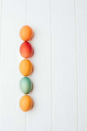 Colored eggs of different sizes on a white wooden background. Symbol of the Easter holiday. Easter background, top viewの写真素材