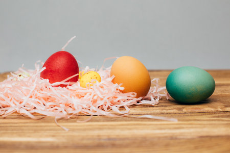 Colored eggs of different sizes on a brown wooden background. Symbol of the Easter holiday. Easter background, front viewの写真素材