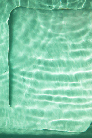 Abstract nature textured background, water waves in the pool with sun reflection, clear green waterの写真素材