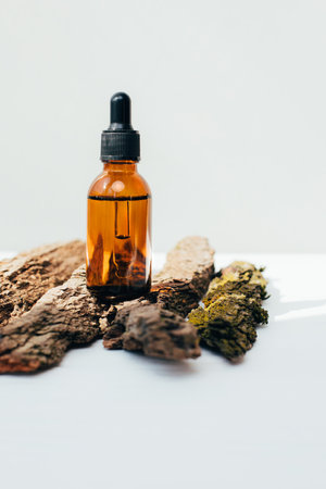 Amber bottle with facial treatment on a dry bark on a white background. Front viewの写真素材