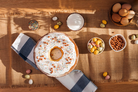 Round Easter cupcake decorated with white protein cream and colorful sprinkles on a wooden table in...