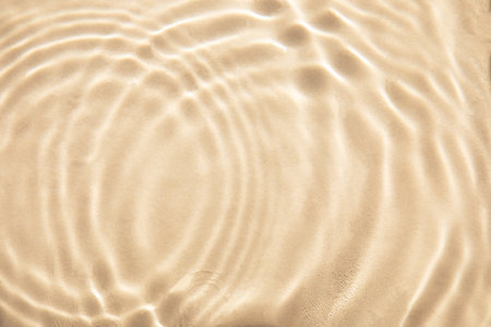 Abstract nature textured background, water waves in the pool with sun reflection. Clear water with bubbles and circles on beige backgroundの写真素材