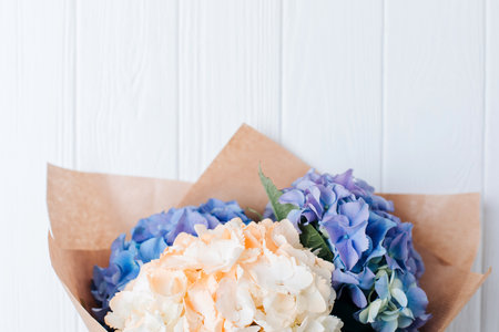 Bouquet of purple, blue and yellow hydrangeas on a white wooden table. Flowers background. Front viewの写真素材