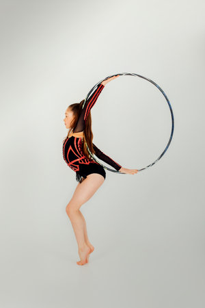 A girl gymnast in a black leotard with a with hoop on a white background. Rhythmic gymnastics concept. Front viewの写真素材