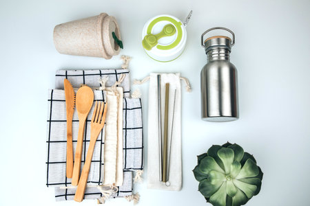 Set of eco friendly products, zero waste concept. Tin can for water and bamboo cutlery on textile...
