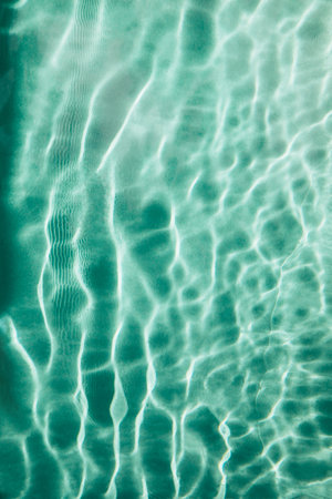 Abstract nature textured background, water waves in the pool with sun reflection, clear green waterの写真素材