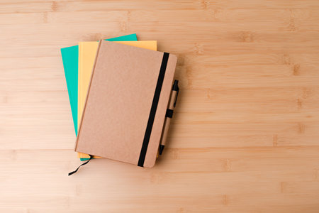 Template with stationery. Green, brown and yellow notebooks on a wooden, bamboo background. Flat lay. Copy spaceの写真素材