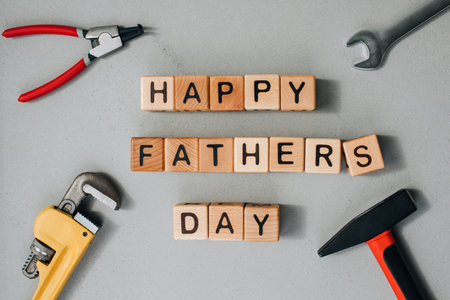 Happy fathers day concept. Background, congratulatory card. Wooden cubes with black letters laid out on a gray concrete background with repair tools. Flat layの写真素材