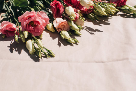 Gently pink eustomas on the beige background. Natural background with a bouquet of flowers with copy space. Flat layの写真素材