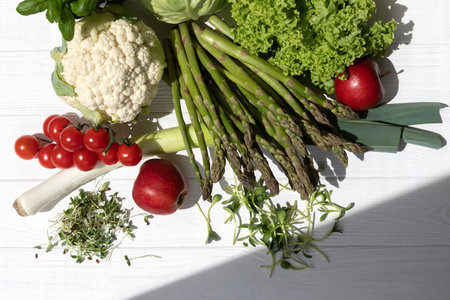 Set of fresh vegetables, asparagus, tomatoes, cabbage, cauliflower, green salad, basilica and apples on white wooden background. Flat layの写真素材