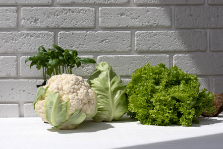Set of fresh green vegetables, asparagus, cabbage, cauliflower, green salad, basilica on white wooden table. Front viewの写真素材