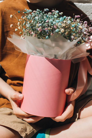 In boys hands bouquet of dry multicolored flowers close-up in pink round box. Gift from boy. Front viewの写真素材