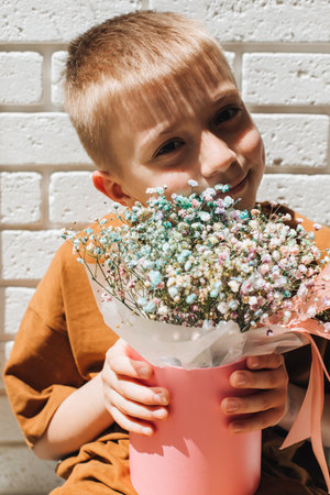 In boys hands bouquet of dry multicolored flowers close-up in pink round box. Gift from boy. Front viewの写真素材
