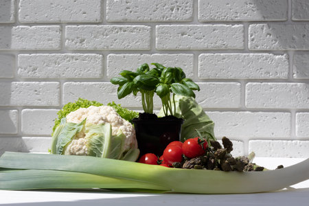 Set of fresh vegetables, asparagus, tomatoes, cabbage, cauliflower, green salad, basilica on white wooden table. Front viewの写真素材