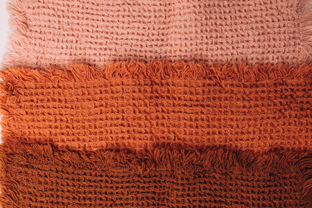 Background for design. Waffle fabrics in orange, brown and pink with fringes. Top viewの写真素材