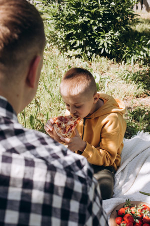 Family picnic. Dad and son in a green garden in sunny weather on a picnic eating pizza. Top viewの写真素材