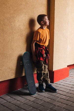 Outdoor activities for children. A cheerful young boy in bright clothes with a skateboard against the backdrop of a colorful wall. Caucasian schoolboy on a walk. Front viewの写真素材