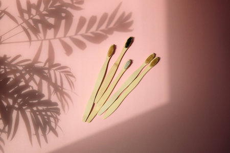 Wooden, bamboo toothbrushes on a pink background with palm shadows. Eco friendly products. Flat layの写真素材
