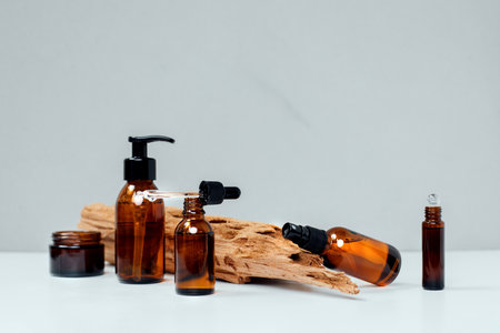 Amber bottles with facial treatment on a wooden stand on a white table. Front viewの写真素材