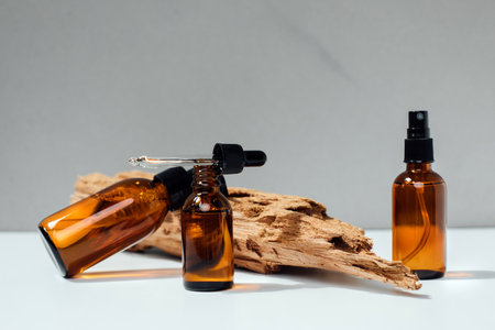 Amber bottles with facial treatment on a wooden stand on a white table. Front viewの写真素材