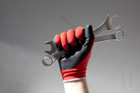 Working tools for repair. Man in denim holding grey wrenches in his hands. Front viewの写真素材