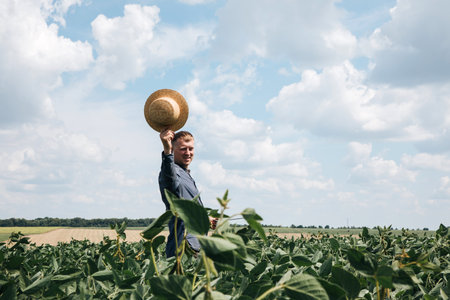 Farmer, agronomist in the soybean field. Controlling the growth of agricultural crops. Green soy with beans. Front viewの写真素材