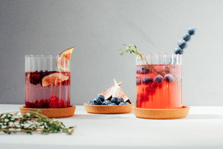 Drinks with with berries and fruits in transparent glasses on a concrete background. Lemonade with ice, refreshing drinks. Fruit lemonade with fig, blueberry. Front viewの写真素材