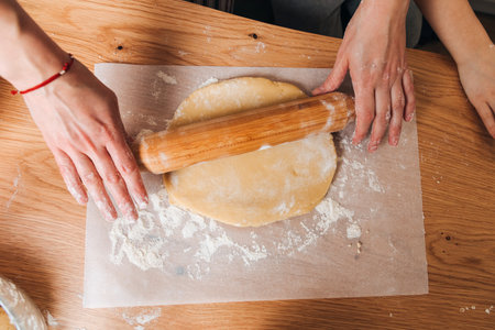 Mom and son are kneading dough for cookies at a wooden table in the kitchen. Cooking desserts at home. Joint activities with children. Top viewの写真素材