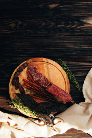 Sausage of different types and sizes on a round wooden plate. Set of smoked sausage. Top viewの写真素材
