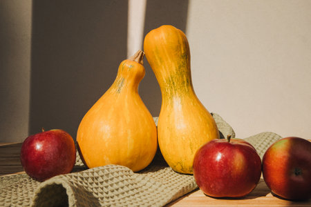 Yellow pumpkins on a light background with red apples on green towel. Autumn composition. Halloween background. Front viewの写真素材
