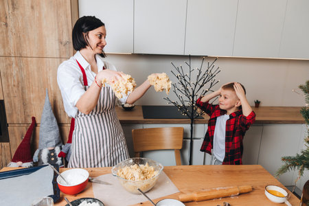 Mom and son are preparing dough for cookies at a wooden table in the kitchen. Cooking desserts at home. Joint activities with children. Front viewの写真素材