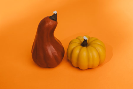 Wax yellow and red candles in the form of pumpkin on an orange seamless background. Autumn, Halloween background. Top viewの写真素材