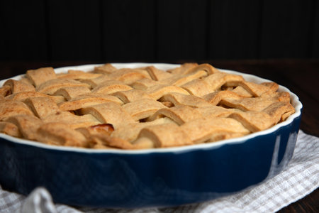 Apple pie in blue form on a dark wooden background with a gray kitchen towel. Ready pie. Front viewの写真素材