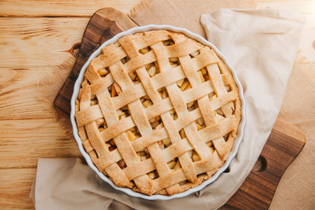Apple pie in blue form on a light wooden background with a brown kitchen towel. Ready pie. Top viewの写真素材