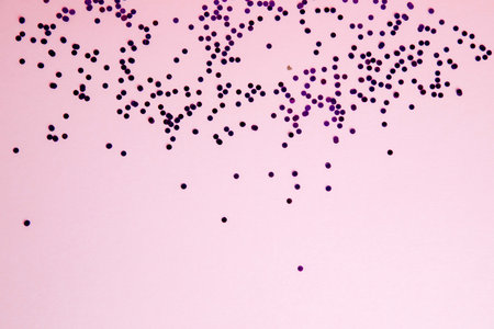 Christmas greeting background with empty space. Violet sparkle sequins, glitter on a light pink...