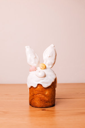 Easter cake is decorated with white meringue with ears and chocolate eggs on a wooden table. Easter...