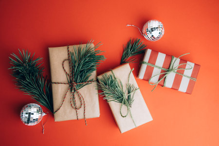 Greeting Christmas, new years background. Gifts wrapping in brown and red paper on a red background with pine branches. Top viewの写真素材
